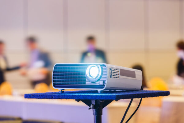 Close up projector in conference room with blurry people background